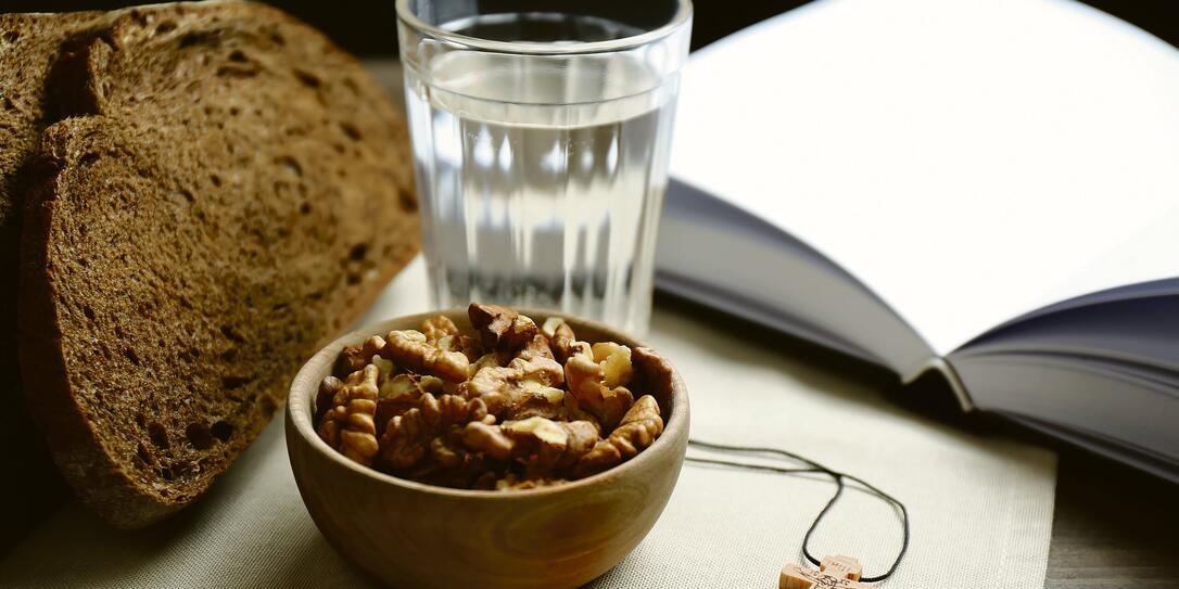 Bread, walnuts, water, Bible and crucifix on table. Great Lent season